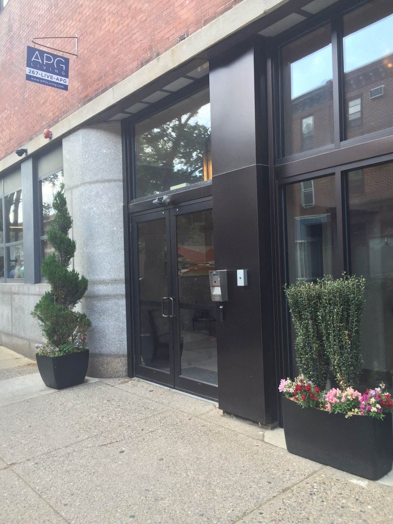 the front of the building with black doors and plants