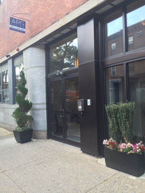 the front of the building with black doors and plants