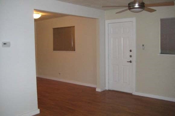 an empty living room with a white door and a ceiling fan