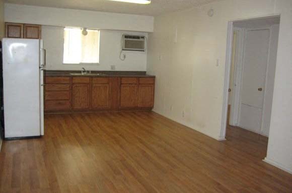an empty kitchen with wooden floors and a refrigerator