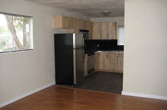 a kitchen with a black refrigerator and wooden cabinets