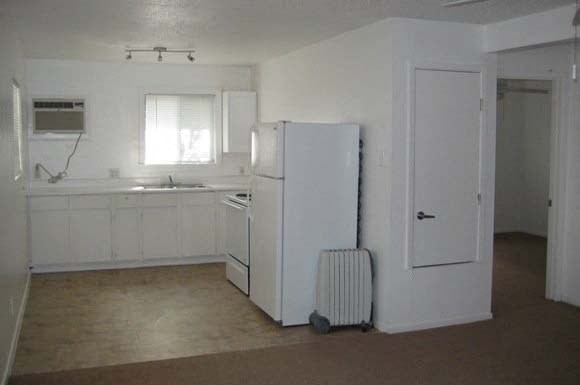 an empty kitchen with a refrigerator and a sink