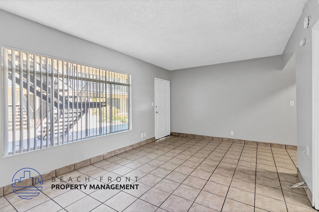 an empty living room with a large window and tiled floors