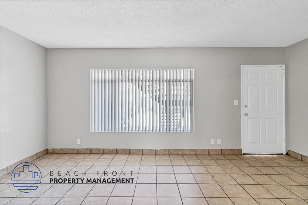 an empty living room with a window and a white door