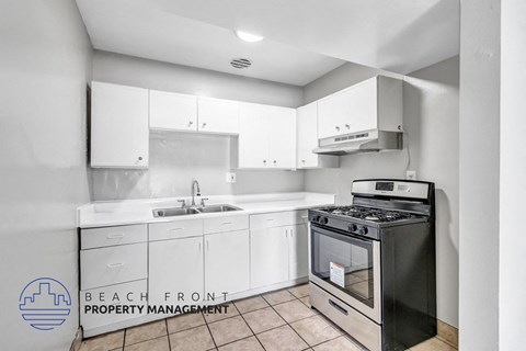 A kitchen with a black stove top oven and white cabinets.