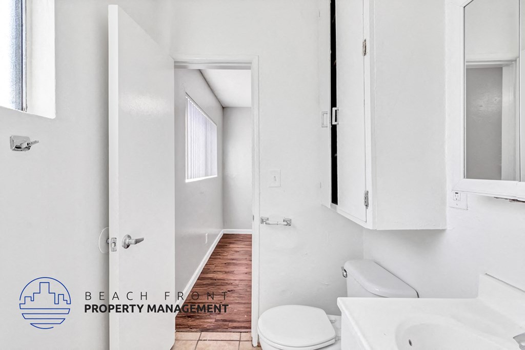 a bathroom with white cabinets and a white toilet and sink