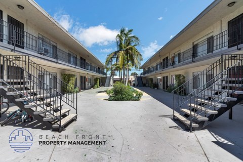 A sunny day at the beachfront property with palm trees and balconies.