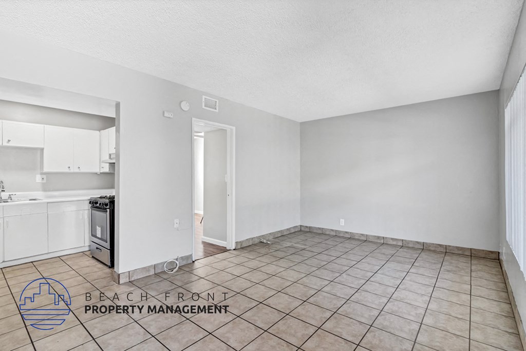 the living room and kitchen of an empty apartment with tile flooring