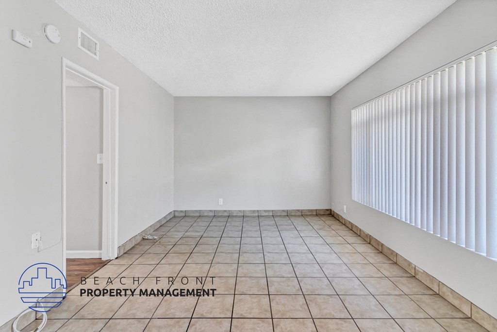 an empty living room with a large window and a tiled floor