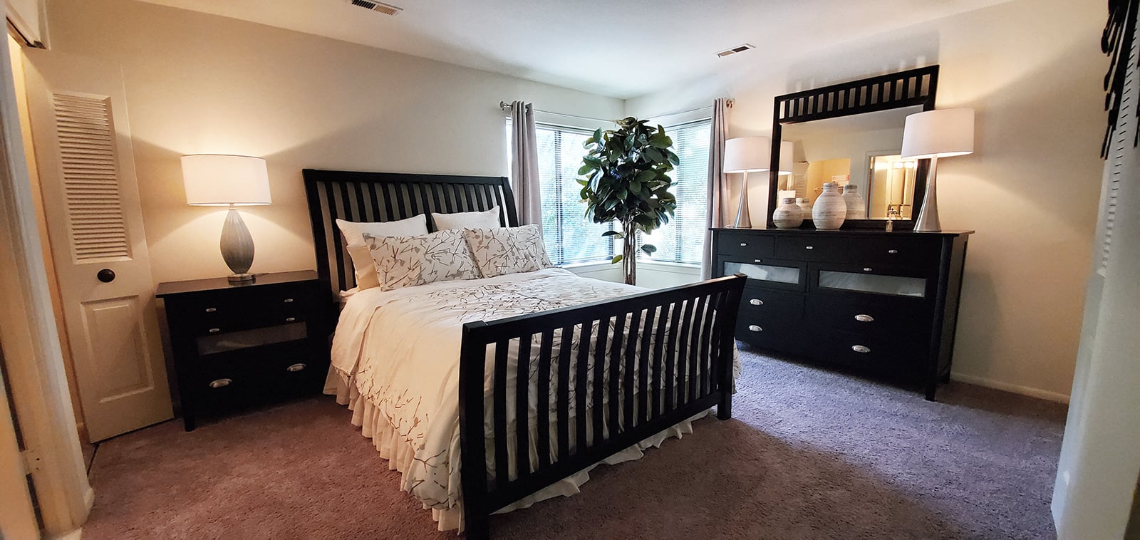 A bedroom with a large bed and a dresser with a mirror.
