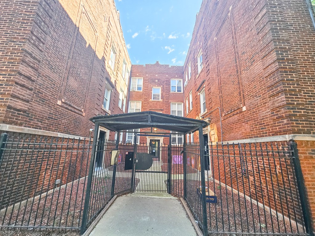 the gate to the courtyard of a brick building