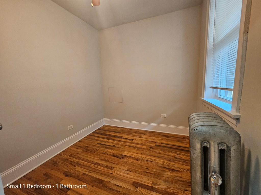 the bedroom of a house with wood flooring and a radiator