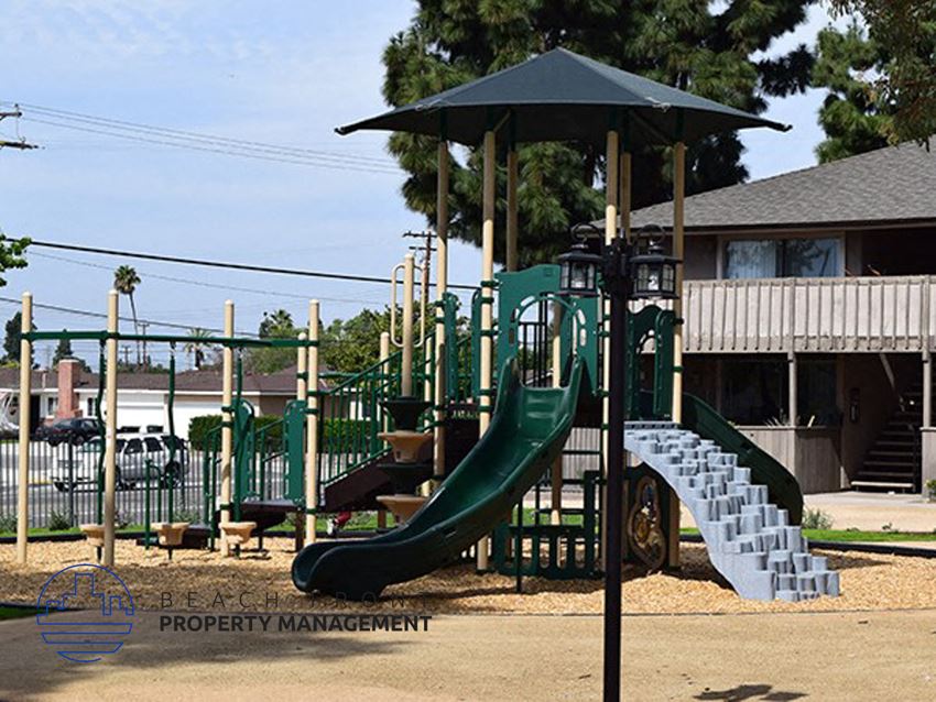 a playground with a slide and a swing set in front of a house
