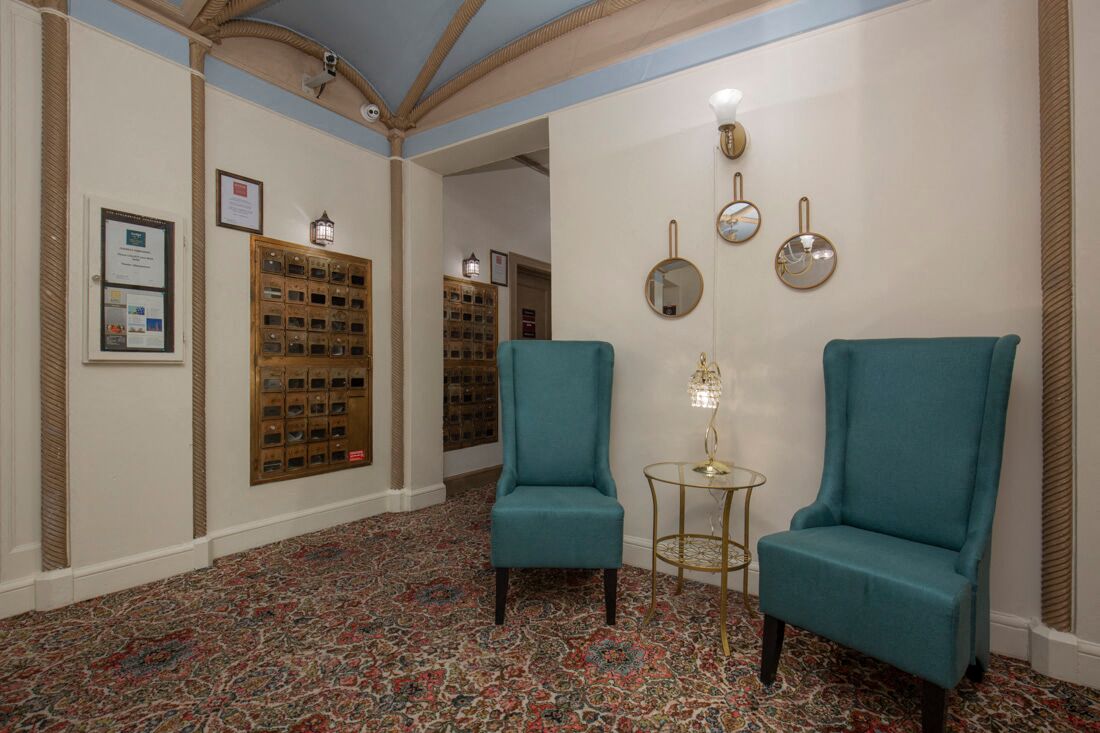Lobby with two blue cozy chairs, pattered carpeting, detailed moldings, and blue painted ceilings at Stockbridge Apartment Homes, Seattle, Washington