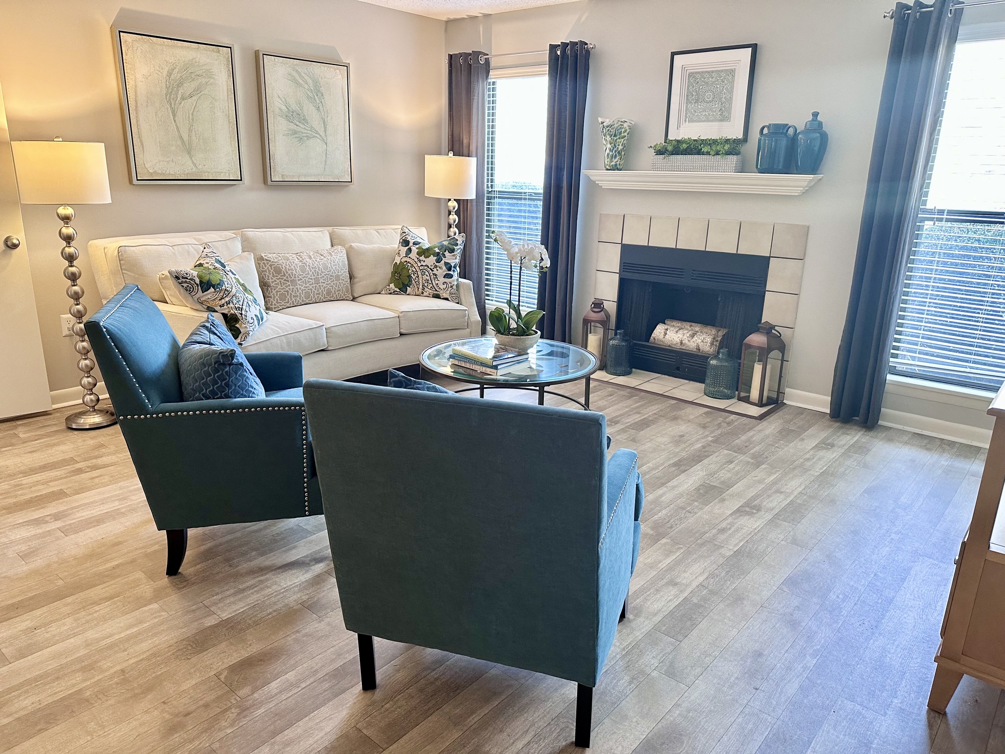 a living room with blue chairs and a white couch and a fireplace