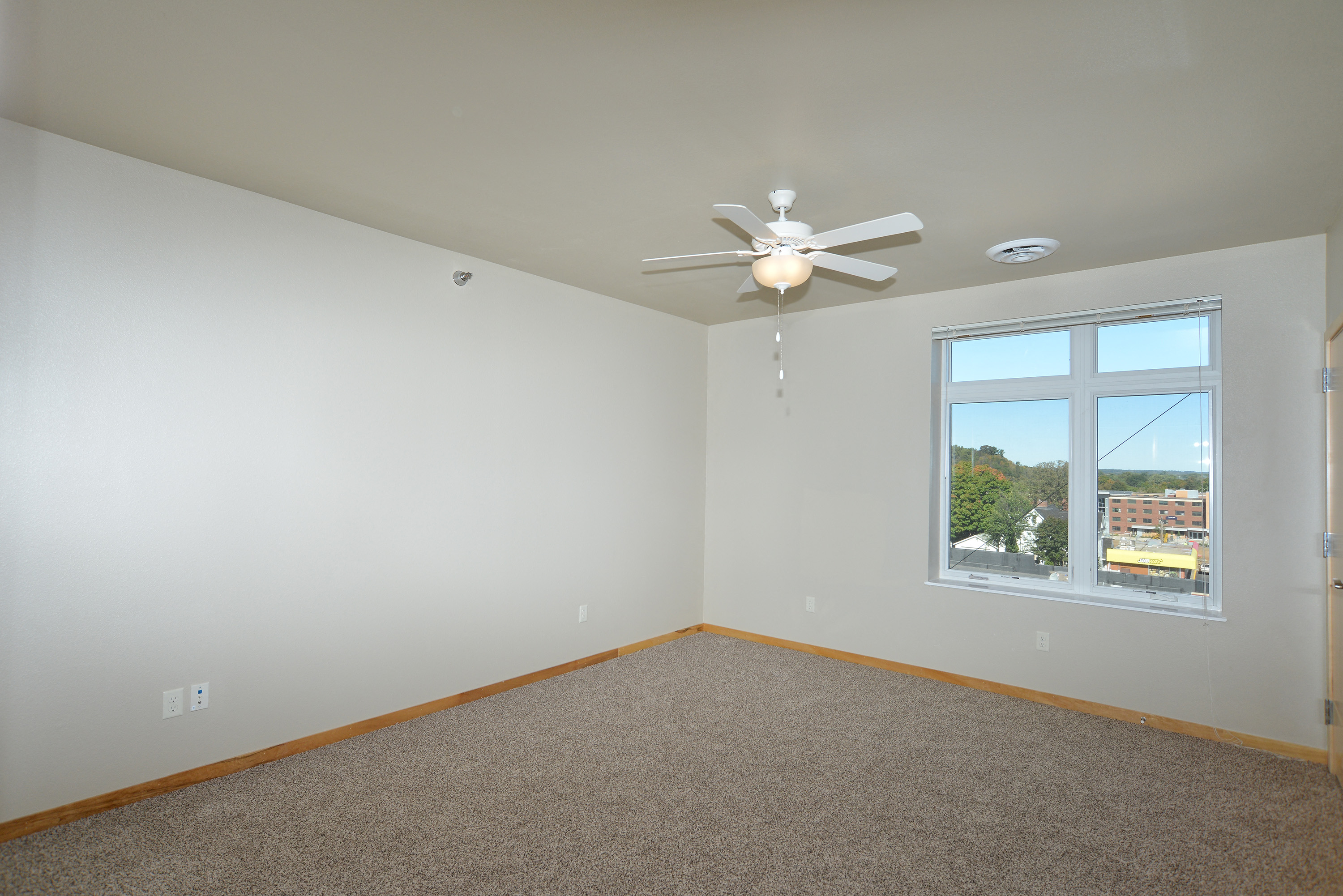 an empty room with a ceiling fan and a window