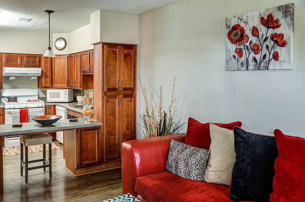 a living room with a red couch and a kitchen