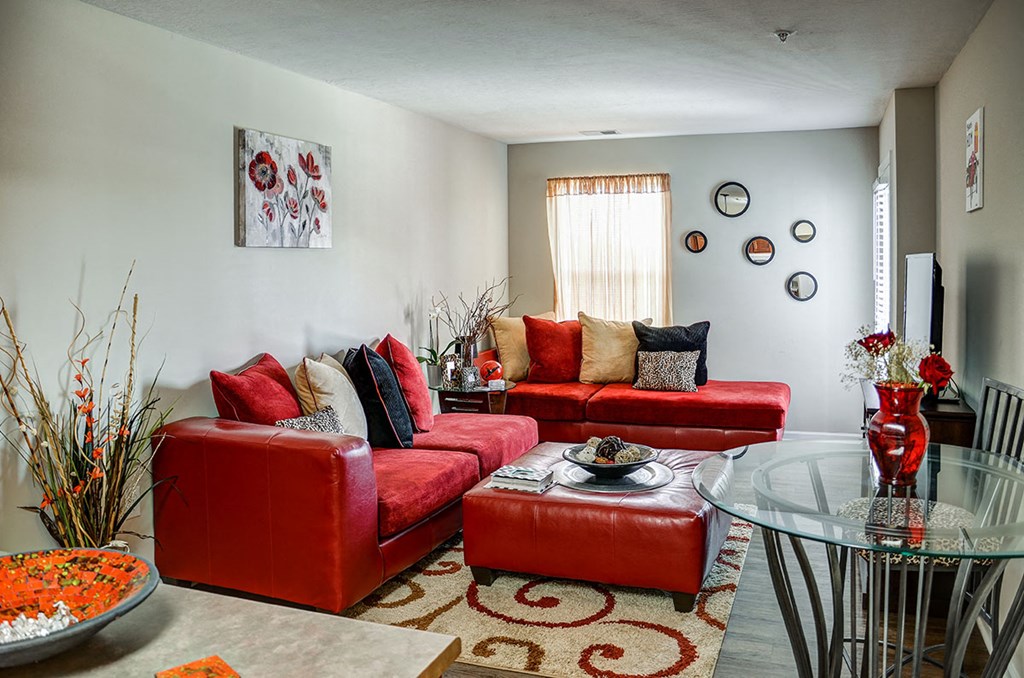 a living room with red leather furniture and a glass table