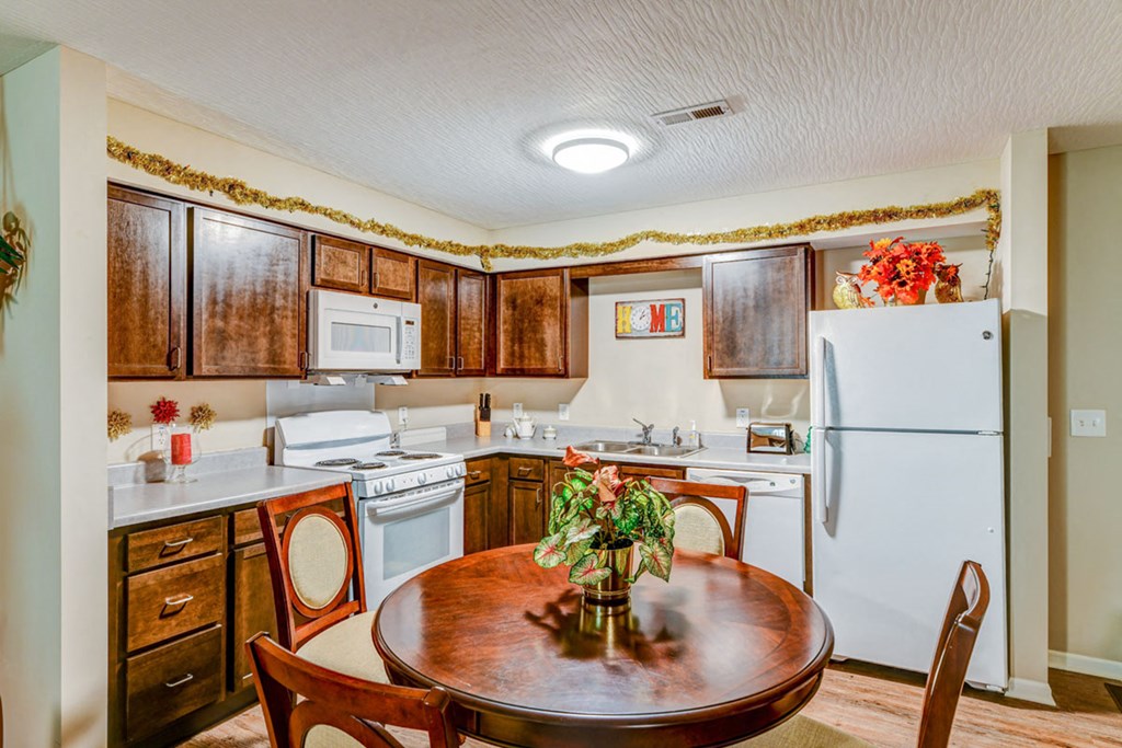 a kitchen with white appliances and a wooden table