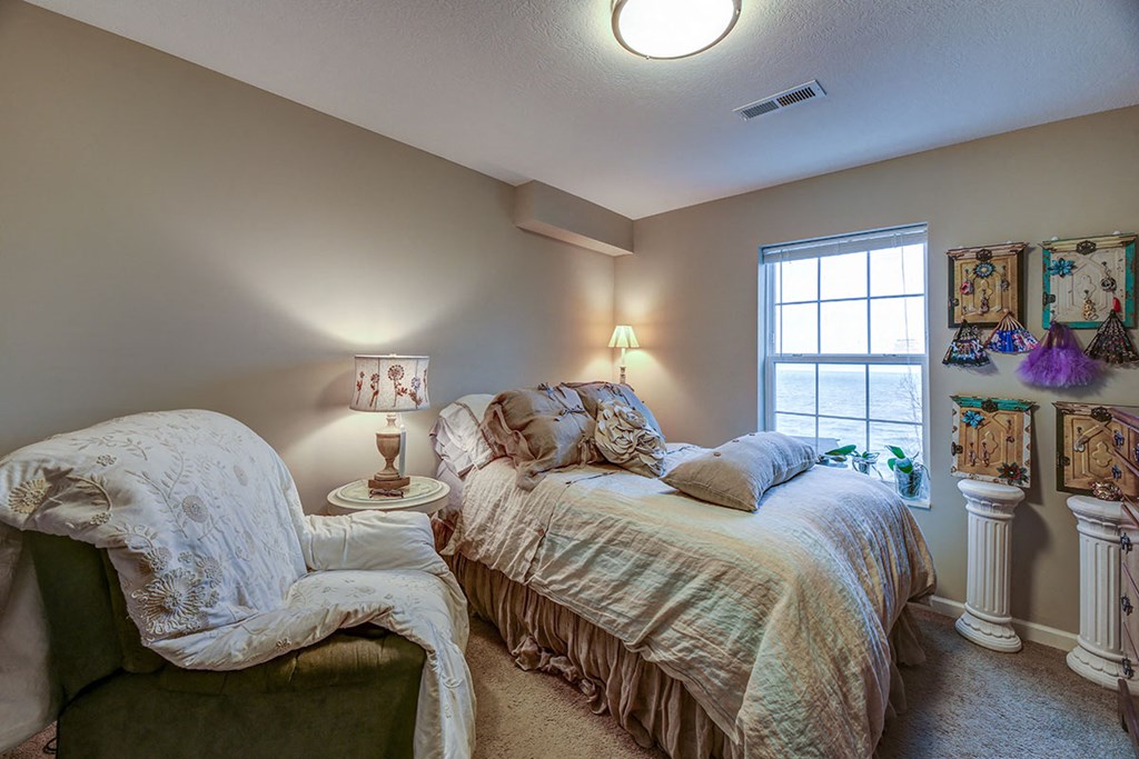 a bedroom with a bed and a chair and a window
