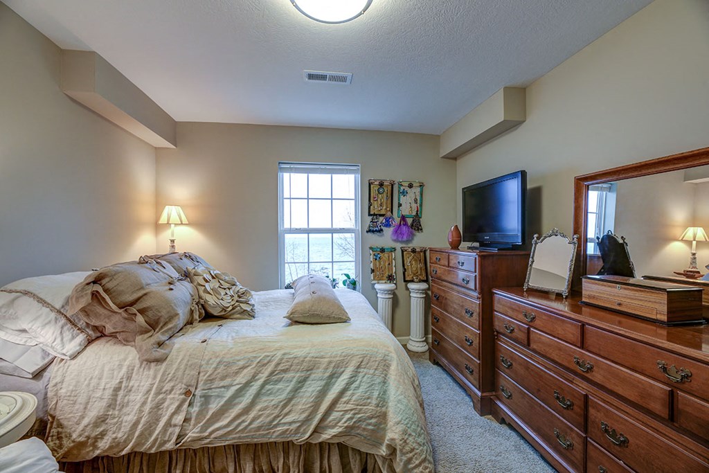 a bedroom with a bed and a dresser and a tv
