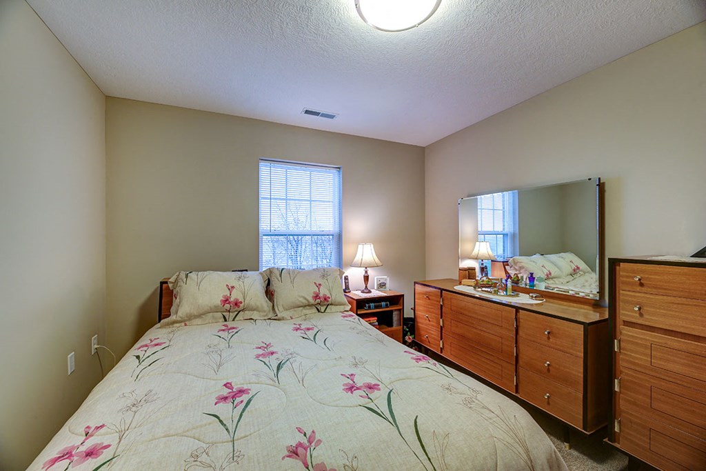 a bedroom with a bed and a dresser with a mirror