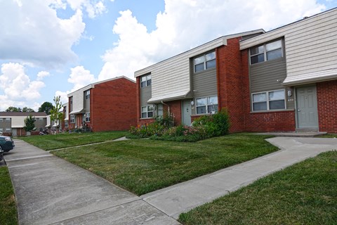 a row of brick apartment buildings with sidewalks and grass