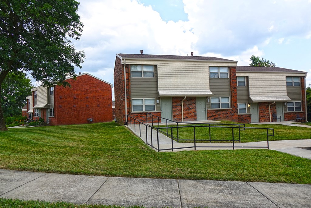 an apartment building with a fenced in yard and stairs