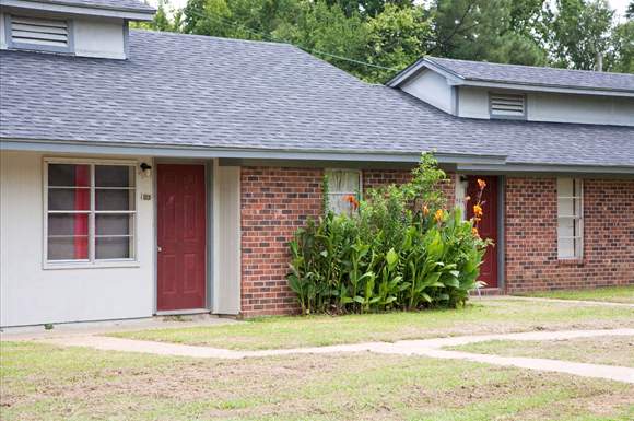 a small brick house with a red door