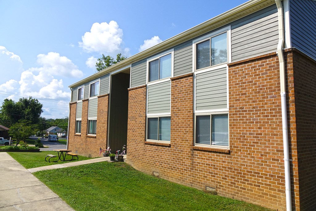 the side of a brick building with a sidewalk and grass