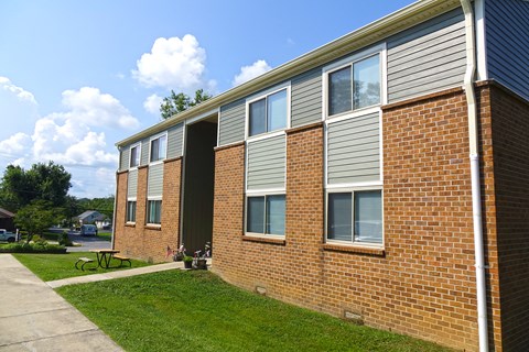 the side of a brick building with a sidewalk and grass