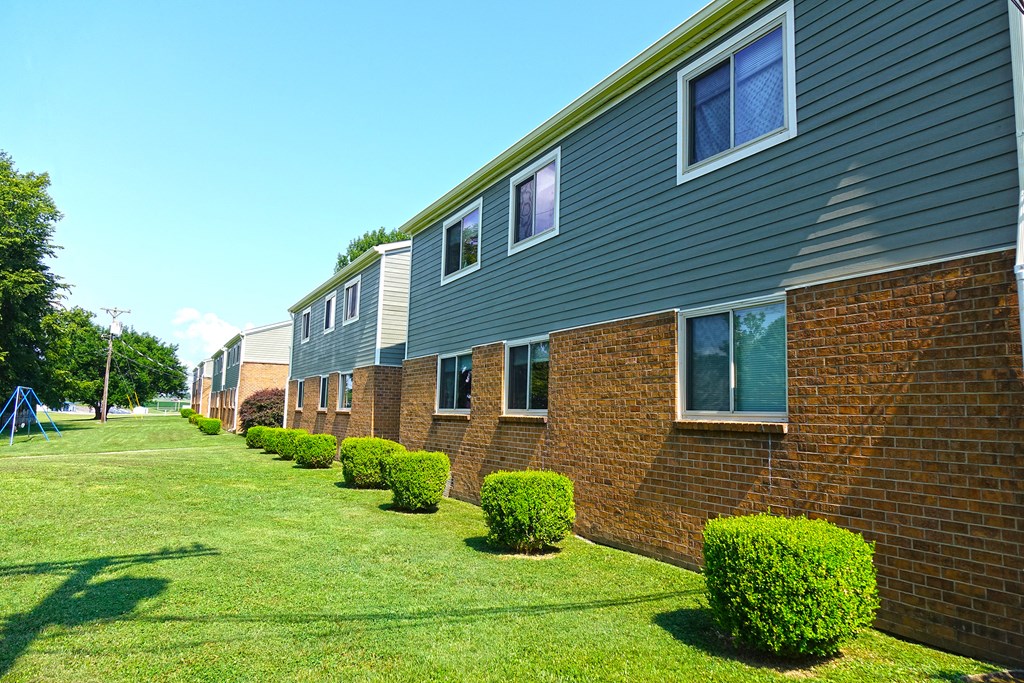 a row of brick apartment buildings with green grass and bushes