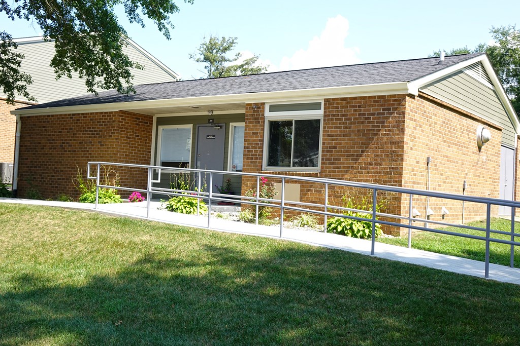 the front porch of a brick house with a white railing