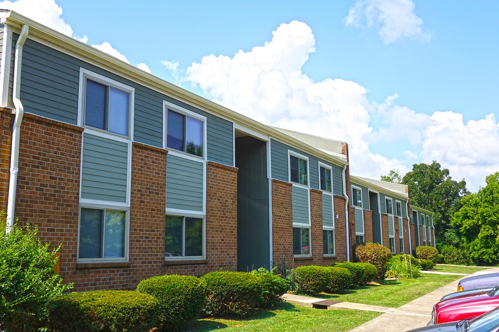 a row of brick apartment buildings with cars parked in front