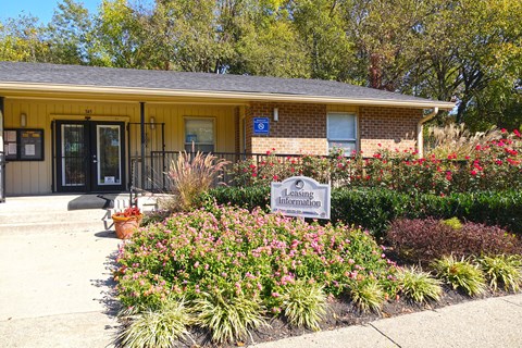a yellow building with a sign in front of a garden