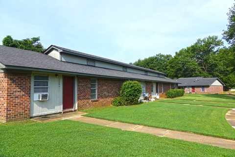 the front of a brick house with a yard and grass