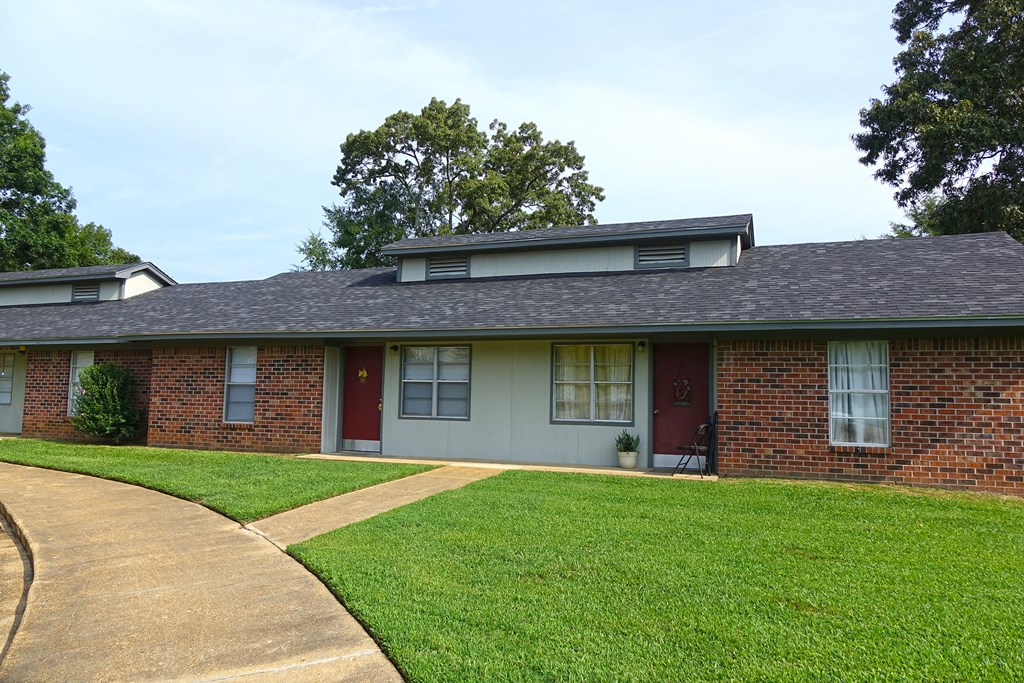 a brick house with a lawn and a sidewalk