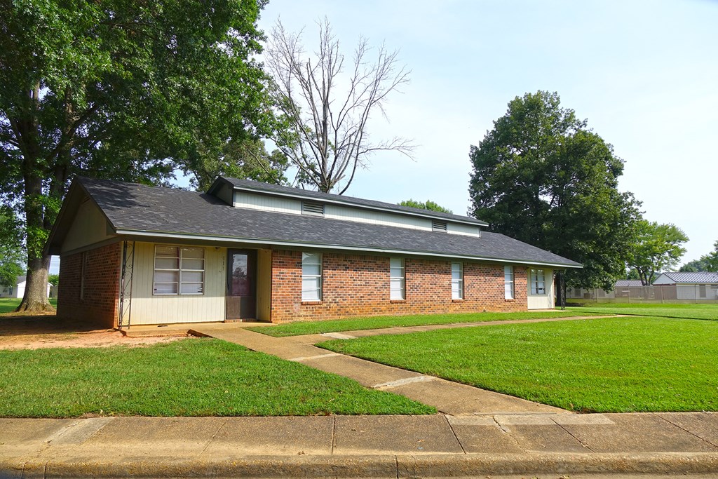 a small brick house with a lawn and a sidewalk