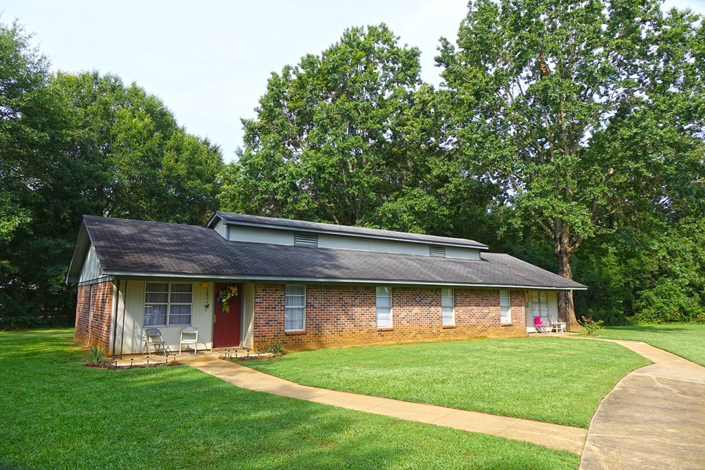 a small brick house with a lawn and trees