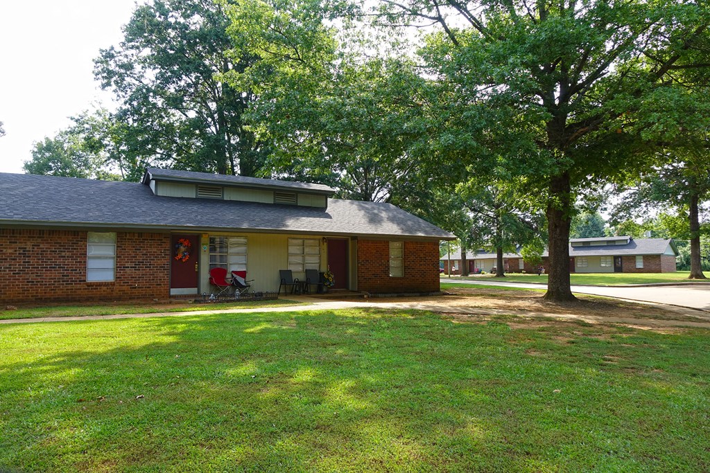 a small brick house with a yard and trees