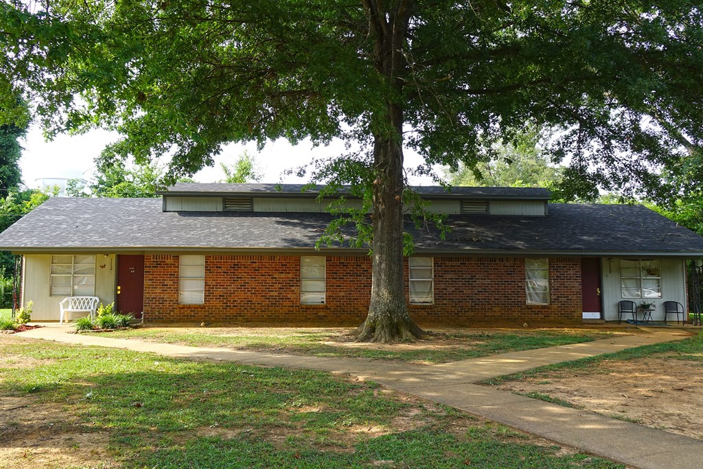 a red brick house with a tree in front of it