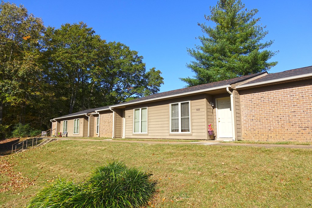 a brick house with a yard and a tree