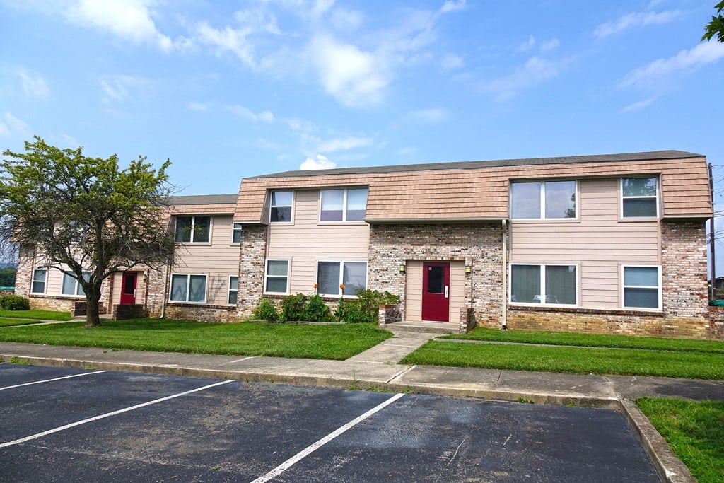 an apartment building with a red door and a lawn