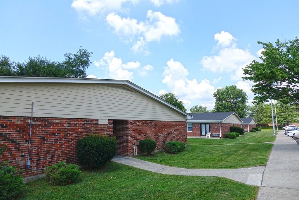 a side view of a brick house with a sidewalk and grass