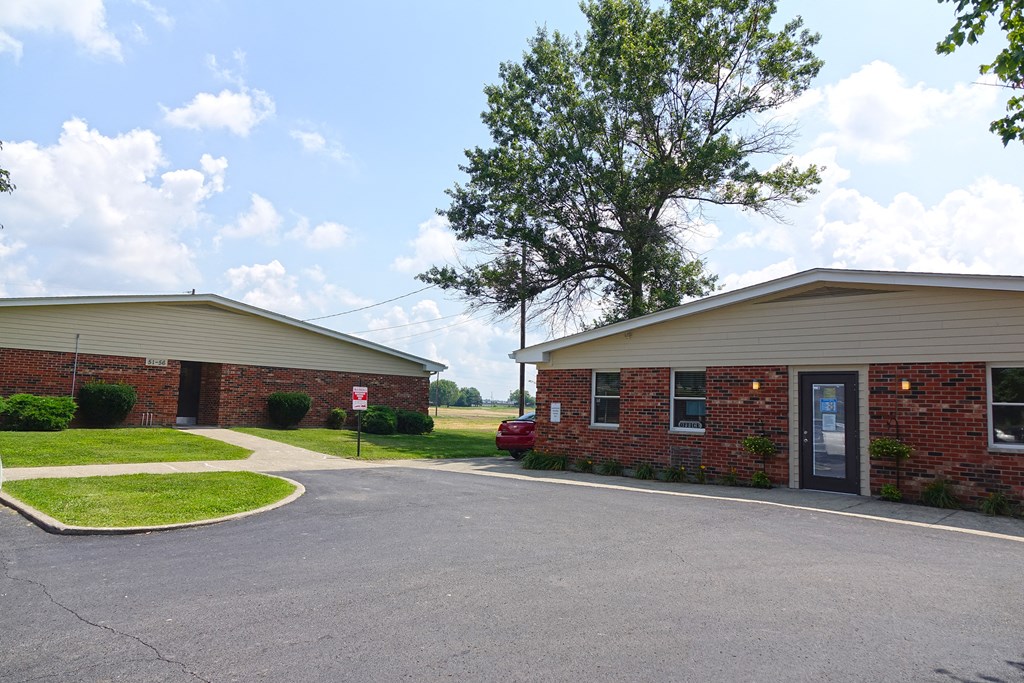 a red brick building with a driveway and a tree in front of it