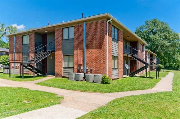 a brick apartment building with stairs and a sidewalk