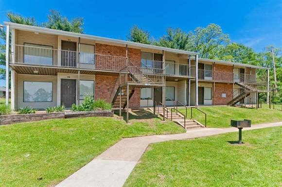 an apartment building with a grass yard and stairs
