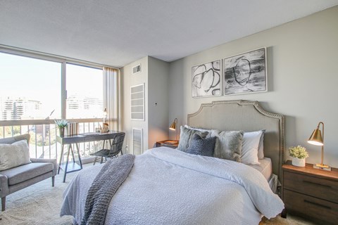 a bedroom with a bed and a desk and a window