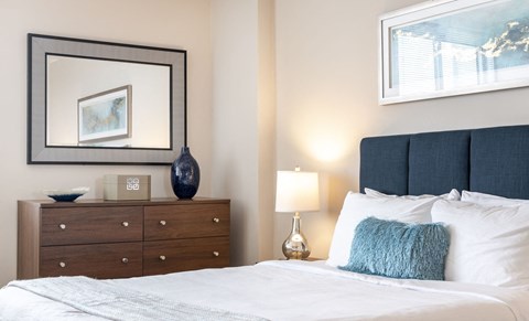 a bedroom with a bed and a dresser with a picture