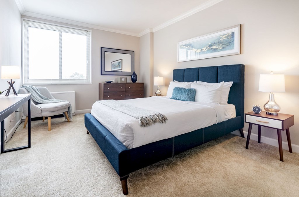 a bedroom with a bed and a chair and a window